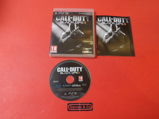 Call of Duty Black Ops II PS3 disc on red background with game case and booklet.