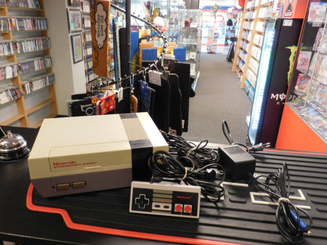 Used Nintendo NES console with original controller and cables displayed in a gaming shop.