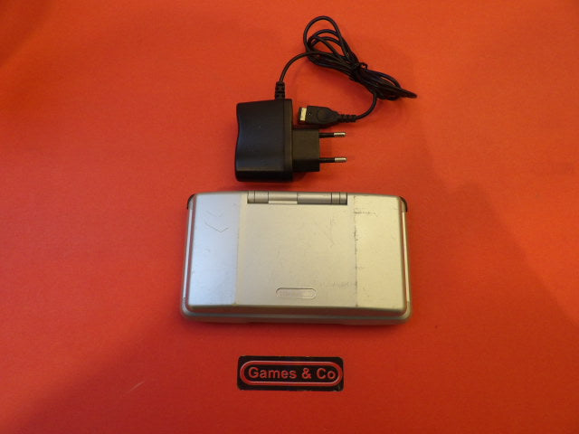 Nintendo DS console with charger on a red background, showcasing the device and power adapter.