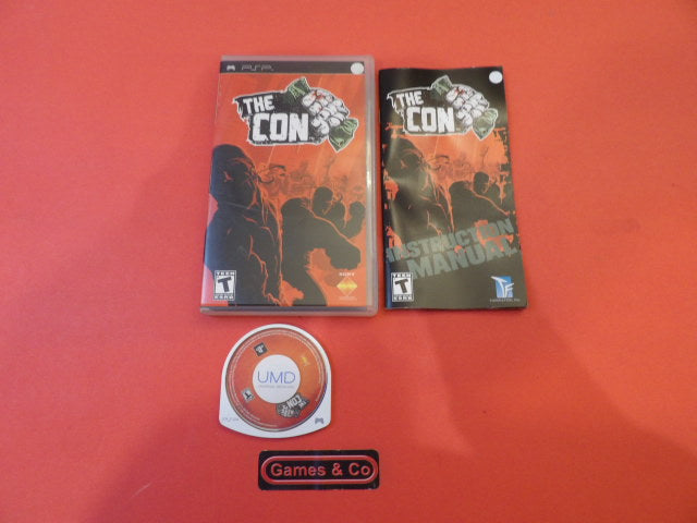 The Con game packaging and UMD for Playstation PSP console displayed on a red background.
