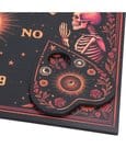 Close-up of gothic spirit board game with plastic planchette and detailed artwork in bold colors.